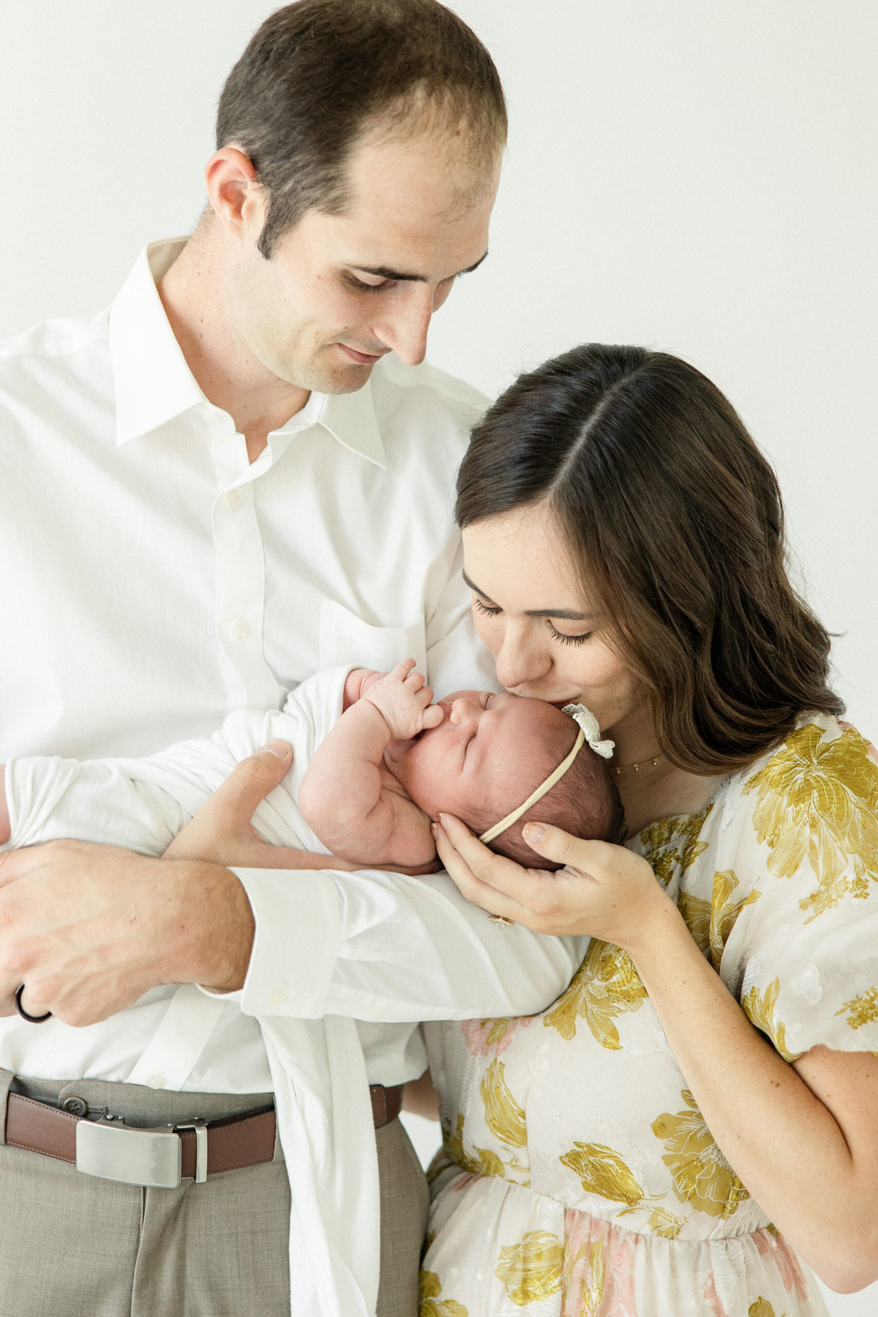 Dad holding a newborn baby wrapped in a white swaddle cuddled in natural-light studio in Hartford SD.